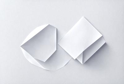 The image features a white paper cut into a triangular shape. The paper is folded into a three-sided structure, creating a unique and interesting visual effect. The paper is placed on a white surface, which further emphasizes the contrast between the paper and the background. The overall atmosphere of the image is creative and artistic, showcasing the intricate design of the paper cutout.