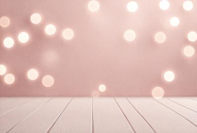The primary subject of the image is a white wooden table with a pink background. The table is adorned with a pattern of lights, creating a visually appealing and warm atmosphere. The setting appears to be a room with a pink wall, and the visual style is a combination of a photo and digital art. The colors and mood of the image are predominantly pink and warm, with the lights adding a touch of brightness and elegance.