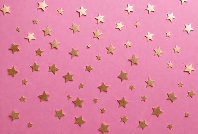 The primary subject of the image is a pattern of stars, which are arranged in a pink background. The setting is a pink surface, and the visual style appears to be a combination of a photo and digital art. The colors and mood of the image are predominantly pink, creating a warm and inviting atmosphere.