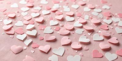 The primary subject of the image is a collection of pink and white hearts. These hearts are scattered across a pink background, creating a visually appealing and romantic scene. The hearts are arranged in various shapes and sizes, adding depth and interest to the overall composition. The visual style of the image is a combination of digital art and illustration, with the hearts appearing as both a pattern and a texture. The dominant colors in the image are pink and white, which evoke a sense of love and warmth.