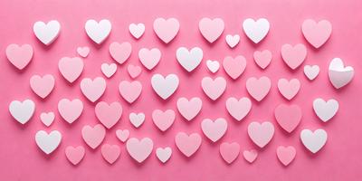 The primary subject of the image is a large number of pink hearts arranged on a pink background. The hearts are white and are scattered all over the background, creating a visually appealing and heartwarming scene. The visual style of the image is a combination of a photo and digital art, as the hearts are arranged in a pattern that gives the impression of a digital design. The colors and mood of the image are predominantly pink, which evokes feelings of love, warmth, and affection.