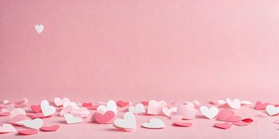 The primary subject of the image is a collection of pink hearts. These hearts are scattered across a pink background, creating a visually appealing and heartwarming scene. The hearts are arranged in various shapes and sizes, adding a sense of depth and variety to the composition. The overall atmosphere of the image is warm, romantic, and inviting.