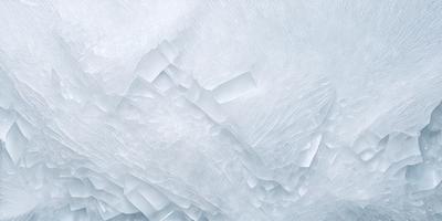 The primary subject of the image is a large, white, and textured surface, which appears to be a piece of ice or a frozen landscape. The setting is a snowy environment, with the background featuring a mountainous landscape. The visual style of the image is a combination of photo and digital art, creating a unique and captivating representation of the subject. The colors and mood of the image are predominantly white and cold, evoking a sense of tranquility and beauty in the snowy landscape.
