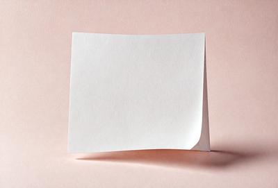 The primary subject of the image is a white piece of paper. The paper is placed on a pink surface, which creates a contrast between the white paper and the pink background. The visual style of the image is a close-up of the paper, showcasing its texture and details. The colors and mood of the image are predominantly pink and white, giving it a clean and simple appearance.