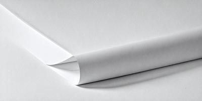 The primary subject of the image is a white sheet of paper. The paper is folded in half, creating a crease. The setting is a white background, which provides a clean and minimalistic appearance. The visual style is a close-up of the paper, highlighting its texture and crease. The colors and mood of the image are predominantly white, giving it a clean and simple appearance.