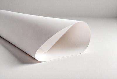 The primary subject of the image is a long, white, rolled-up paper. The paper is placed on a white surface, which serves as the setting and background of the image. The visual style of the image is a photo, capturing the details of the paper and its surroundings. The colors in the image are predominantly white, giving it a clean and minimalist appearance. The overall mood of the image is calm and uncluttered.