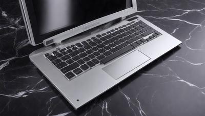 The primary subject of the image is a laptop computer. The laptop is sitting on a black marble countertop, which serves as the setting for the scene. The visual style of the image is a photo, capturing the laptop in its natural environment. The laptop has a silver color, and the overall atmosphere of the image is modern and sleek.