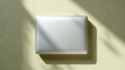 The primary subject of the image is a square white box, which is placed on a marble surface. The setting is a room with a marble wall, and the visual style appears to be a photo. The colors in the image are predominantly white, giving the scene a clean and minimalist appearance.