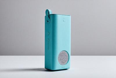 The primary subject of the image is a small, blue electronic device, possibly a cell phone or a music player. The device is placed on a white surface, which serves as the background. The visual style of the image is a close-up of the electronic device, showcasing its design and features. The colors in the image are predominantly blue and white, giving the scene a clean and modern appearance.