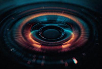 The primary subject of the image is a close-up of a spinning object, possibly a fan or a turbine, with a blue and orange color scheme. The setting is a dark background, which contrasts with the bright colors of the spinning object. The visual style appears to be a digital art or illustration, as the colors and details are vivid and well-defined. The overall atmosphere of the image is dynamic and energetic, as the spinning object creates a sense of motion and activity.