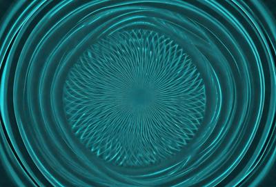 The primary subject of the image is a blue circle with a pattern of swirls or waves. The setting is a blue surface, which could be a wall or a table. The visual style appears to be a digital art or illustration, as the swirls are intricately designed and the overall atmosphere is vibrant and dynamic. The dominant colors are blue and white, creating a sense of depth and movement in the image.