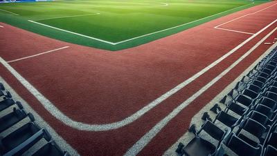 The primary subject of the image is a soccer field with a green surface. The setting is a soccer field with a grassy surface. The visual style is a photo of a soccer field. The colors and mood of the image are predominantly green, which gives a sense of a lush, well-maintained field.