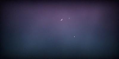 The primary subject of the image is the night sky, which is filled with stars. The setting is a dark, cloudy night, and the visual style is a photo. The colors and mood of the image are predominantly dark and moody, with the stars providing a contrasting brightness.