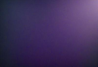 The primary subject of the image is a purple background. The setting is a dark, empty space with no visible objects or people. The visual style is a close-up of the purple background, which creates a moody and atmospheric mood.