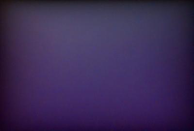 The primary subject of the image is a purple background. The setting is a dark, empty room with a purple wall. The visual style is a close-up of the purple wall, which gives the image a moody and atmospheric feel.
