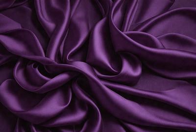 The primary subject of the image is a purple fabric, which is the main object, scene, or focus of the image. The setting is a close-up view of the fabric, showcasing its texture and details. The visual style is a photo, capturing the purple fabric in its natural state. The colors and mood of the image are predominantly purple, creating a calm and soothing atmosphere.