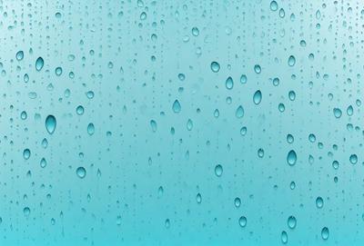 The primary subject of the image is a blue background with water droplets on it. The setting is a clear blue sky, and the visual style is a close-up of the water droplets. The colors and mood of the image are predominantly blue, creating a calm and serene atmosphere.