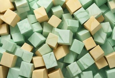 The primary subject of the image is a large pile of green and yellow marble blocks. The setting is a marble-covered surface, which adds to the visual style of the image. The colors and mood of the image are predominantly green and yellow, creating a warm and inviting atmosphere.