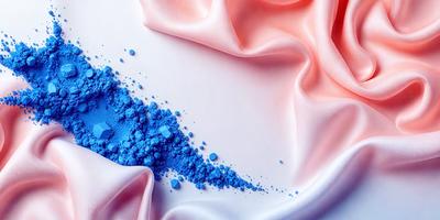 The primary subject of the image is a blue substance, possibly a powder or a liquid, that is spreading or dripping onto a pink surface. The setting appears to be a white table, and the visual style seems to be a close-up or a detailed view of the blue substance. The colors and mood of the image are predominantly pink and blue, creating a contrast between the two colors.