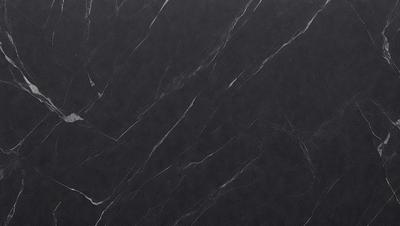 The primary subject of the image is a black marble countertop. The setting is a kitchen, with the countertop being the main focus of the scene. The visual style is a close-up of the marble countertop, showcasing its texture and pattern. The colors and mood of the image are predominantly dark, with the black marble countertop being the main source of contrast.
