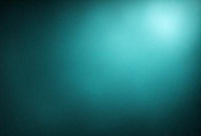 The primary subject of the image is a blue background, which creates a serene and calming atmosphere. The setting is a dark, empty room with a blue wall, and the visual style is a close-up of the blue wall. The colors and mood of the image are predominantly blue, giving it a peaceful and tranquil appearance.