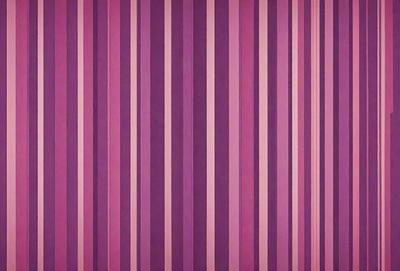The primary subject of the image is a purple and white striped wallpaper. The setting is a room with a purple wall, and the visual style is a patterned wallpaper. The dominant colors are purple and white, creating a calm and soothing atmosphere.