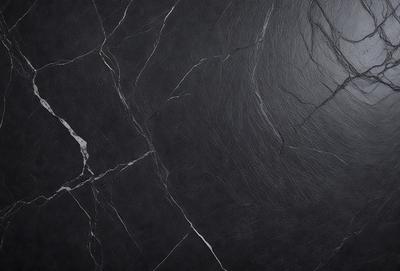 The primary subject of the image is a black marble countertop. The setting is a kitchen, with the countertop being the main focus of the scene. The visual style is a close-up of the marble countertop, showcasing its texture and details. The colors and mood of the image are predominantly dark, with the black marble countertop being the main source of contrast and visual interest.
