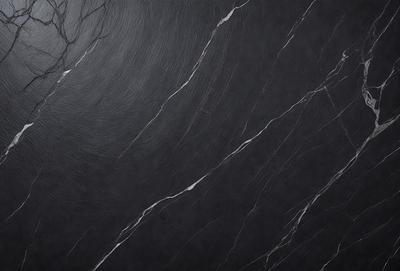 The primary subject of the image is a black marble countertop. The setting is a kitchen, with the countertop being the main focus of the scene. The visual style is a close-up of the marble countertop, showcasing its texture and pattern. The colors and mood of the image are predominantly dark, with the black marble countertop being the main source of contrast.