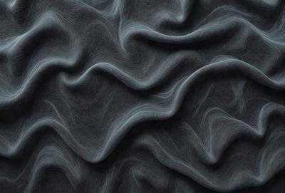 The primary subject of the image is a close-up of a black fabric with a pattern of swirls and waves. The setting is a dark background, which contrasts with the fabric. The visual style is a black and white photo, giving the image a classic and timeless appearance. The dominant colors are black and white, creating a moody and dramatic atmosphere.