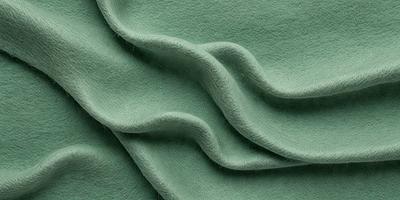 The primary subject of the image is a green fabric, which appears to be a piece of wool. The setting is a close-up view of the fabric, showcasing its texture and color. The visual style is a realistic representation of the fabric, and the colors and mood convey a sense of warmth and coziness.