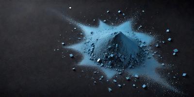 The primary subject of the image is a pile of blue powder, which appears to be a mix of sand and blue paint. The setting is a black surface, possibly a table or a floor. The visual style of the image is a close-up of the blue powder, showcasing its texture and color. The colors and mood of the image are predominantly dark and moody, with the blue powder standing out as the main focal point.
