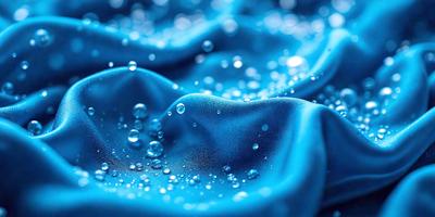 The primary subject of the image is a blue cloth with water droplets on it. The setting is a blue background, and the visual style appears to be a photo. The dominant colors are blue and white, creating a calm and serene atmosphere.