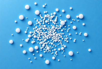 The primary subject of the image is a close-up of a blue background with numerous white spheres scattered across it. The setting appears to be a blue surface, possibly a wall or a table. The visual style of the image is a combination of a photo and digital art, as the spheres are arranged in a pattern that gives the impression of a digital design. The colors in the image are predominantly blue and white, creating a calm and serene atmosphere.