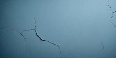 The primary subject of the image is a large crack in a blue surface, which appears to be a piece of paper or a wall. The setting is a close-up view of the crack, with the background being the blue surface. The visual style is a close-up, and the colors and mood are predominantly blue, giving the image a calm and serene atmosphere.