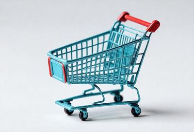 The primary subject of the image is a blue plastic shopping cart. The cart is positioned on a white surface, which serves as the background. The visual style of the image is a combination of photo and digital art, as it appears to be a realistic representation of a shopping cart. The dominant colors in the image are blue and white, creating a clean and modern atmosphere.
