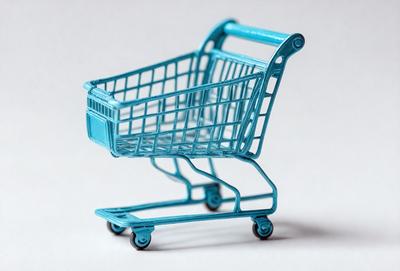 The primary subject of the image is a blue plastic shopping cart. The cart is placed on a white surface, which serves as the setting or background. The visual style of the image is a close-up of the shopping cart, showcasing its details. The dominant colors in the image are blue and white, creating a clean and modern atmosphere.
