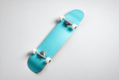 The primary subject of the image is a blue skateboard with white wheels. The skateboard is placed on a white surface, which serves as the setting or background. The visual style of the image is a photo, capturing the skateboard in detail. The dominant colors in the image are blue and white, creating a clean and modern atmosphere.