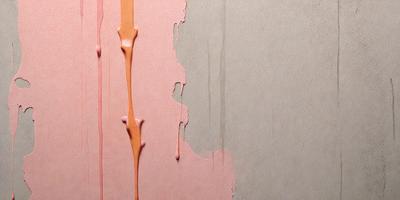 The primary subject of the image is a wall with a pink background. The setting is a room with a peeling wall, and the visual style is a photo. The dominant colors are pink and orange, creating a warm and inviting atmosphere.