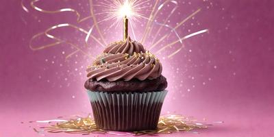 The primary subject of the image is a chocolate cupcake with a lit candle on top. The cupcake is placed on a pink surface, which adds a contrasting color to the scene. The visual style of the image is a close-up of the cupcake, highlighting its details and texture. The colors and mood of the image are warm and celebratory, as the lit candle suggests a special occasion or a birthday celebration.