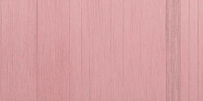 The primary subject of the image is a wooden wall with a pinkish hue. The setting is a room with a pink wall, and the visual style is a close-up of the wall. The colors and mood of the image are predominantly pink, creating a warm and inviting atmosphere.