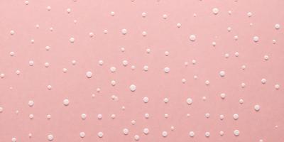 The primary subject of the image is a pink background with white dots. The setting is a close-up of the pink background, which creates a visually appealing and contrasting effect. The visual style is a combination of a pattern and a texture, giving the image a unique and artistic appearance. The colors and mood of the image are predominantly pink and white, creating a warm and inviting atmosphere.