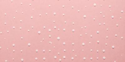 The primary subject of the image is a pattern of white dots on a pink background. The setting is a wall, and the visual style appears to be a combination of a photo and digital art. The colors and mood of the image are predominantly pink and white, creating a clean and elegant appearance.