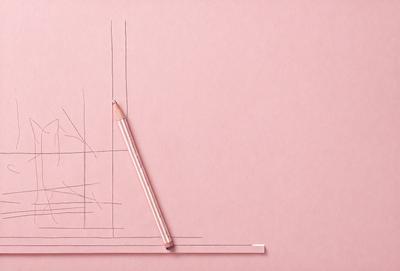 The primary subject of the image is a pencil, which is placed on a pink surface. The setting is a room with a pink wall, and the visual style appears to be a drawing or illustration. The colors and mood of the image are predominantly pink, creating a warm and inviting atmosphere.
