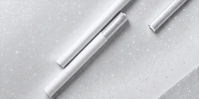 The primary subject of the image is a pair of white cigarettes. The setting is a white background, which creates a clean and minimalist appearance. The visual style is a close-up of the cigarettes, emphasizing their shape and texture. The colors and mood of the image are predominantly white, giving it a simple and elegant feel.