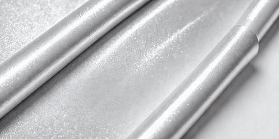 The primary subject of the image is a silver metal surface, possibly a metal sheet or a metal bar. The setting is a white background, which contrasts with the silver metal. The visual style is a close-up of the metal surface, showcasing its texture and reflective properties. The colors and mood of the image are predominantly silver and white, giving it a clean and modern appearance.