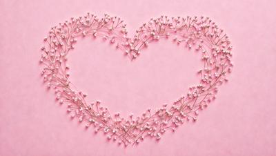 The primary subject of the image is a heart-shaped arrangement of pink flowers. The heart is made up of many small flowers, creating a visually appealing and delicate design. The heart is placed on a pink background, which adds to the overall warm and romantic atmosphere of the scene. The visual style of the image is a combination of digital art and illustration, as it is a carefully crafted and detailed design.