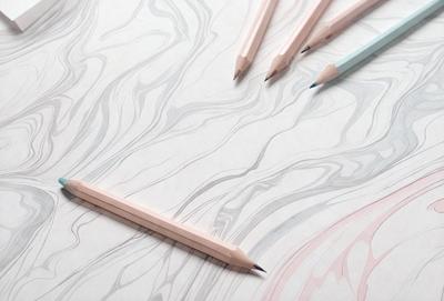 The primary subject of the image is a pencil, which is placed on a piece of paper. The setting is a table, and the visual style is a close-up of the pencil. The colors and mood of the image are predominantly white, as the paper and pencil are both white.