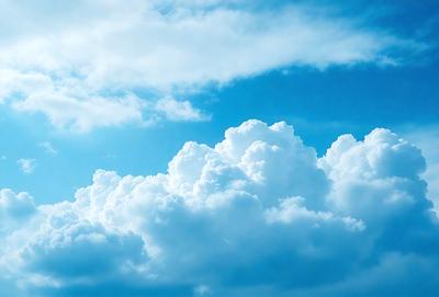 The primary subject of the image is a large, fluffy cloud in the sky. The cloud is the main focus of the image, and it appears to be a natural, outdoor scene. The setting is a clear blue sky, which provides a contrasting backdrop for the cloud. The visual style of the image is a photo, capturing the beauty of the cloud in its natural environment. The colors and mood of the image are predominantly blue, with the cloud being the main source of visual interest and creating a sense of