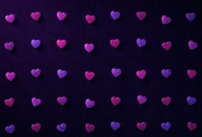 The primary subject of the image is a large number of purple hearts arranged in a pattern. The hearts are scattered across a purple background, creating a visually appealing and colorful scene. The visual style of the image is a combination of digital art and illustration, with the hearts appearing as a pattern or design. The dominant colors in the image are purple and pink, giving the scene a warm and inviting atmosphere.