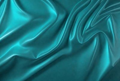 The primary subject of the image is a close-up of a blue fabric, possibly a piece of silk or velvet. The setting is a dark background, which contrasts with the vibrant blue fabric. The visual style appears to be a photo, as the fabric is captured in detail. The colors and mood of the image are predominantly blue, creating a calm and serene atmosphere.